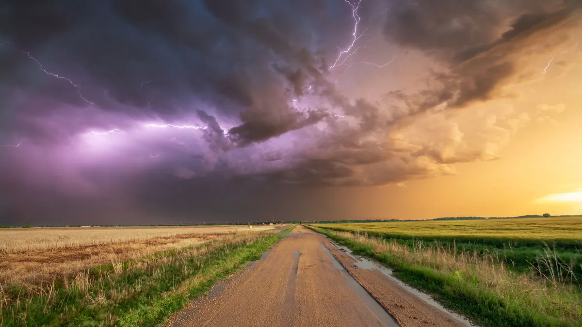A thunderstorm with lightning over a wheat field and a dirt road in Oklahoma