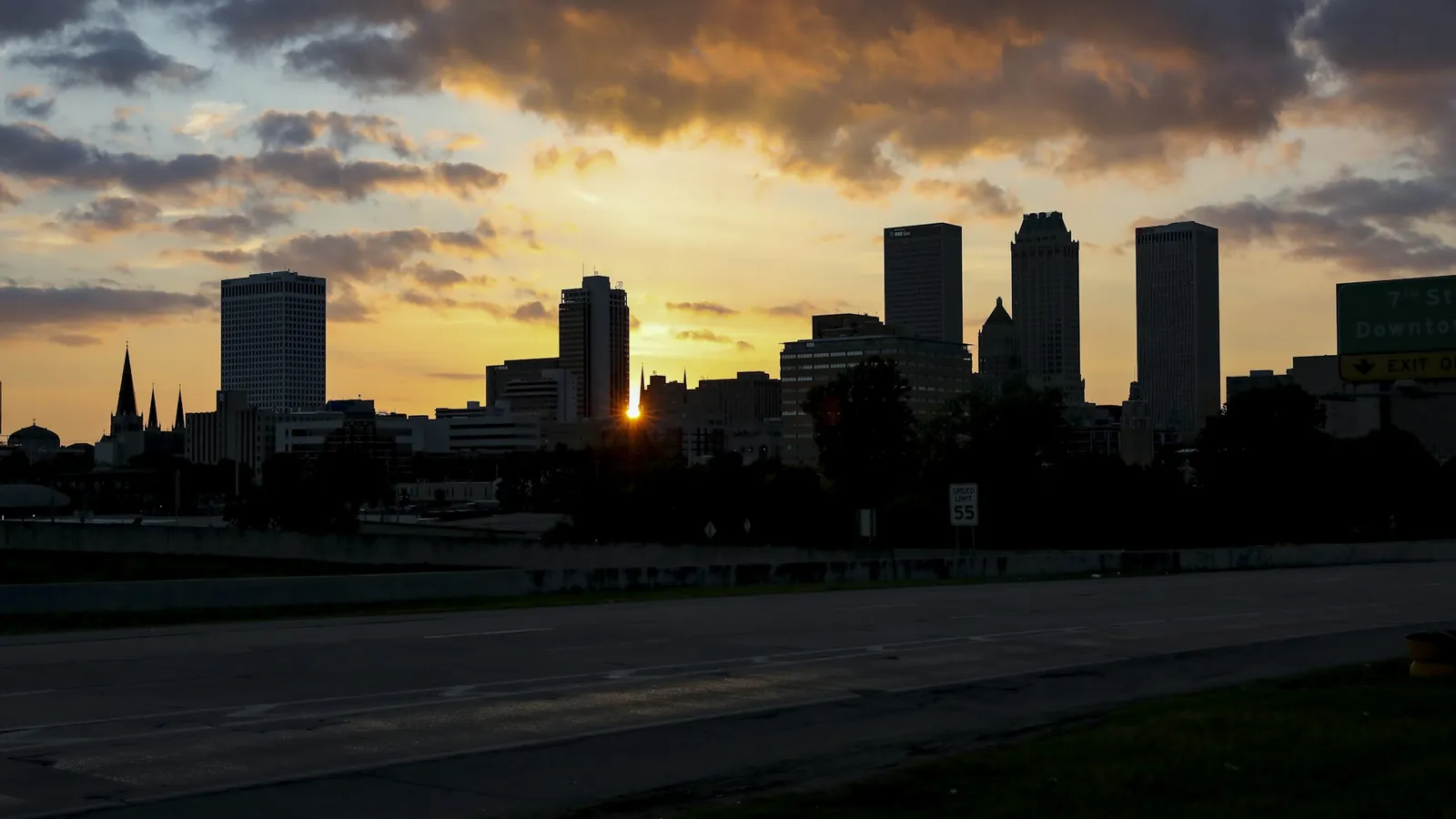 The downtown Tulsa skyline at sunset under a cloudy sky